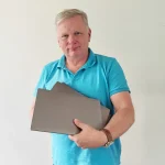 Mann mit drei silbernen Laptops im Arm